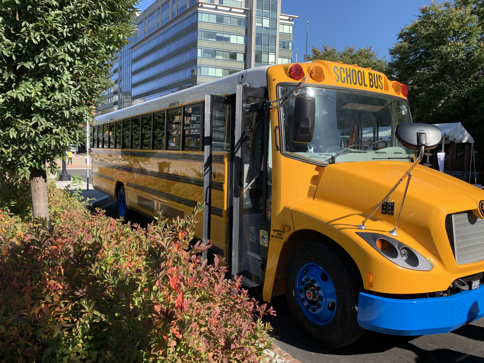 A modern looking yellow school bus parked on a city street.